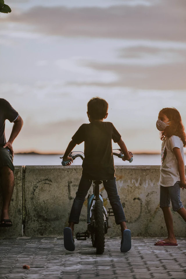Two boys and a girl on a concrete wall — photograph by Ibrahim Ifaaz