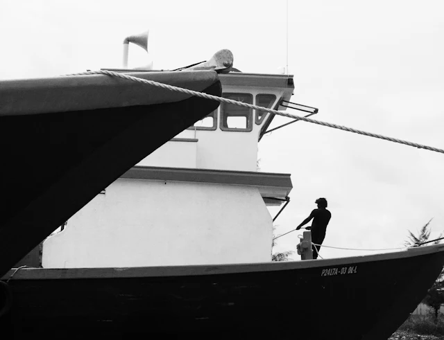 Man standing on a boat — photograph by Ibrahim Ifaaz, Maldives